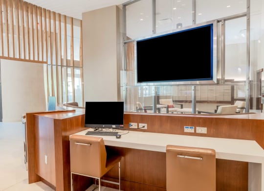 a desk with a computer and a monitor in a lobby at The Acadia at Metropolitan Park, Arlington, VA